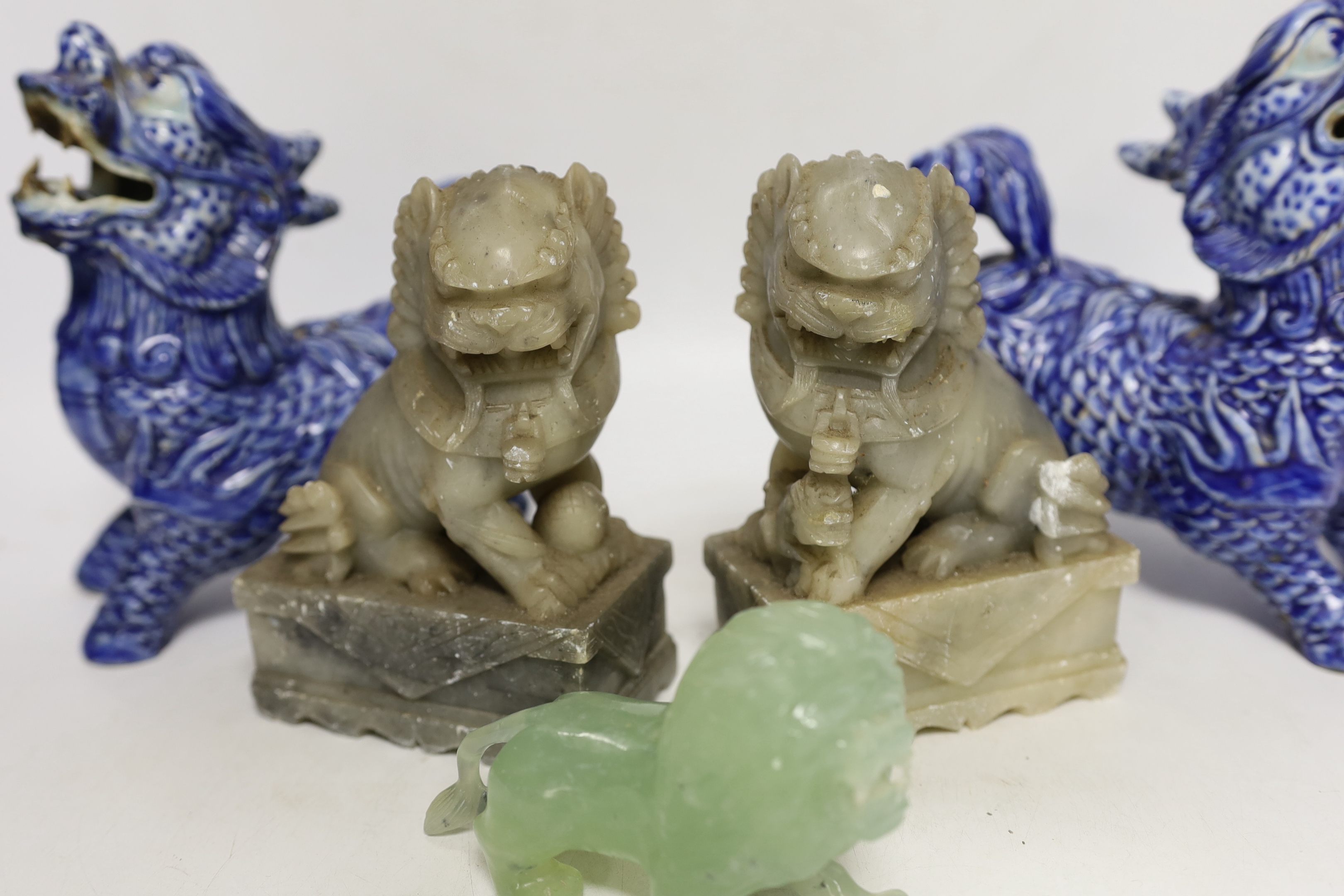 Two pairs of Chinese lion dogs; a blue and white porcelain set and a carved soapstone set, together with a carved jade lion, tallest 18cm (5)